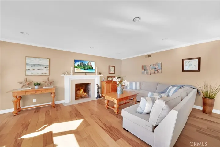 Walls Removed for a True Open Concept Floorplan. Living Room with Hardwood Flooring, Crown Molding, Bay Window, Recessed Lighting, and a Quartz Fireplace with Handcrafted Wood Manel and surround.