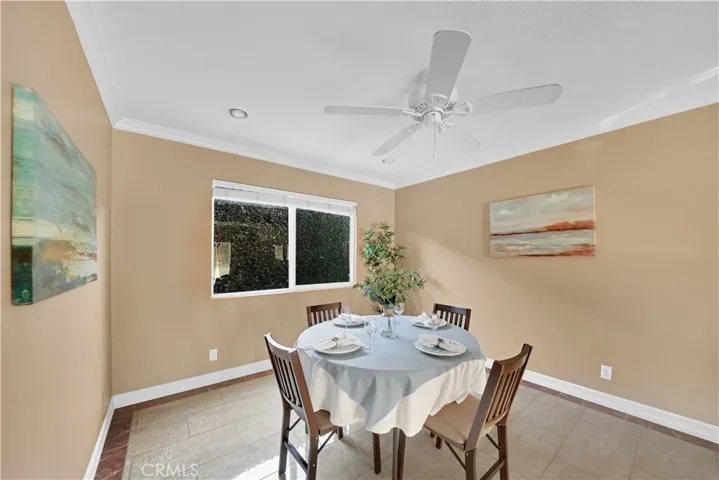 Dining Room Adjacent to the Living Room in the Downstairs Unit with Crown Molding, Ceiling Fan, Recessed Lighting, High Baseboards, and Marble-Type Tile Flooring
