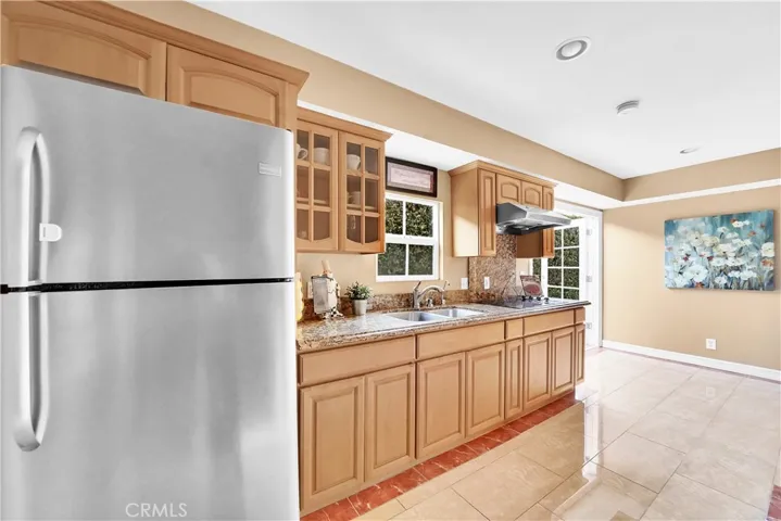 This is the Kitchenette in the Downstairs Unit. It has Granite Counters, Custom Cabinetry with Glass Display Panels, Stainless Sink, Electric Cooktop, Hood/Vent, Recessed Lighting, Marble-Type Tile Flooring, Breakfast Nook, and French Doors that Open to the Backyard Patio
