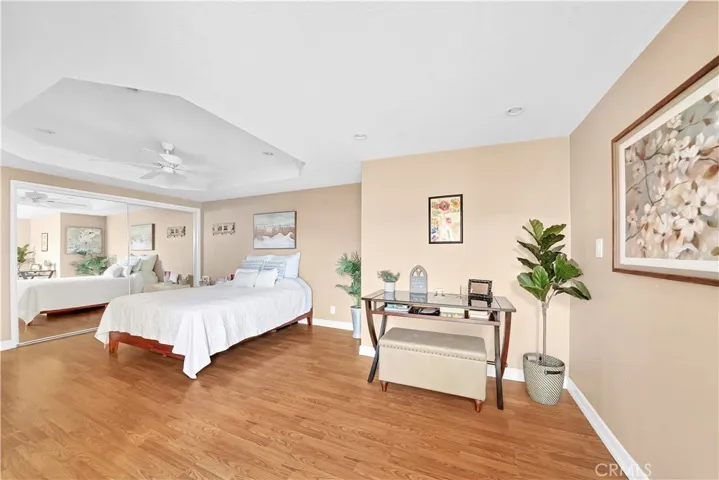 Large Downstairs Primary Suite Features Retreat Area, Coffered Ceiling, Recessed Lighting, Ceiling Fan, Wood Laminate Flooring, Mirrored Closets, French Doors to Courtyard, and Beautiful Ensuite Granite Bathroom