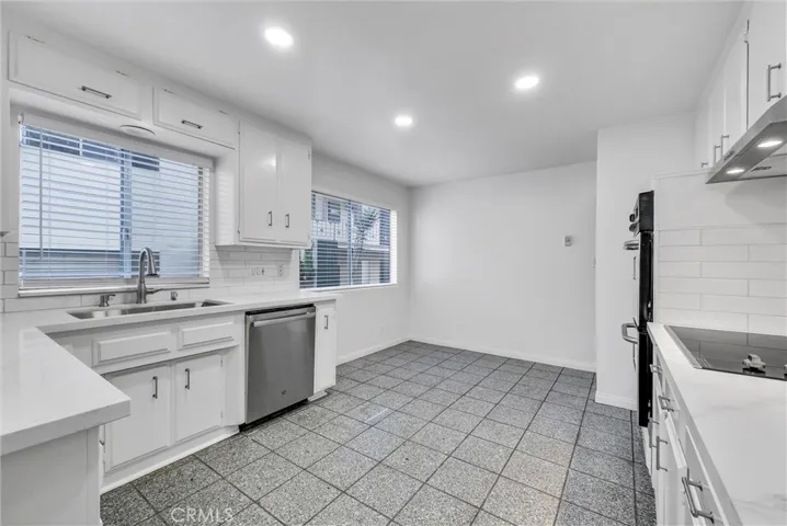 East view of kitchen w/ new quartz countertop, stainless steel sink, dishwasher, hood, cooktop, and double stable oven.