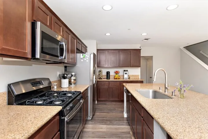 Kitchen boasts stainless appliances and cherrywood stained cabinets