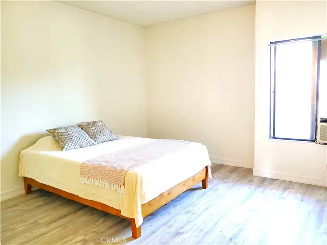 Primary bedroom with window A/C unit and laminate flooring.