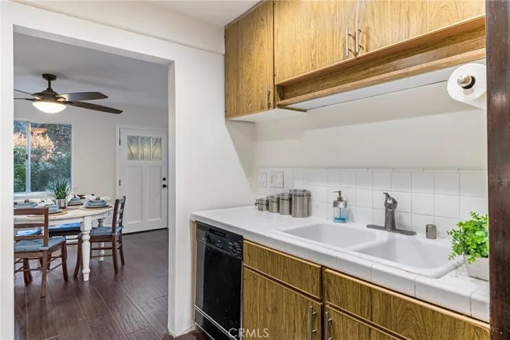 Kitchen with dark hardwood floors, while tile counters, and laminate wood cabinetry