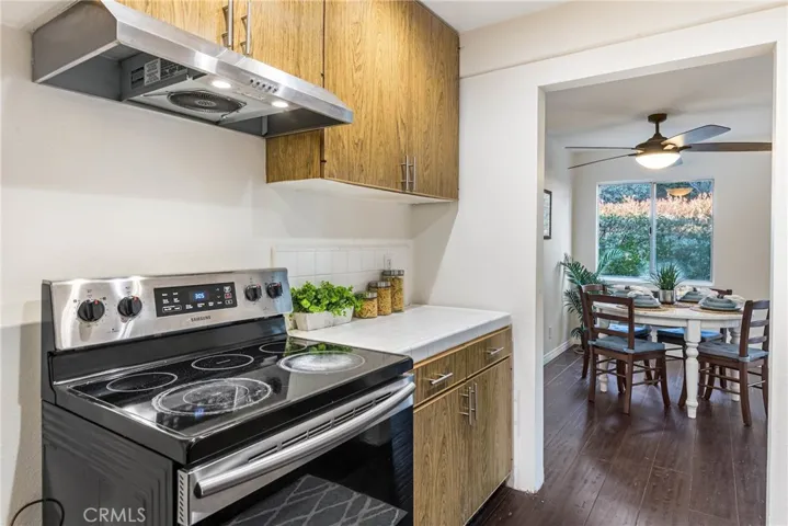 Kitchen with dark hardwood floors, while tile counters, and laminate wood cabinetry