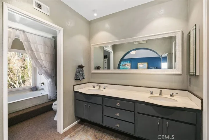 Primary bathroom with double sinks, separate tub and toilet area.