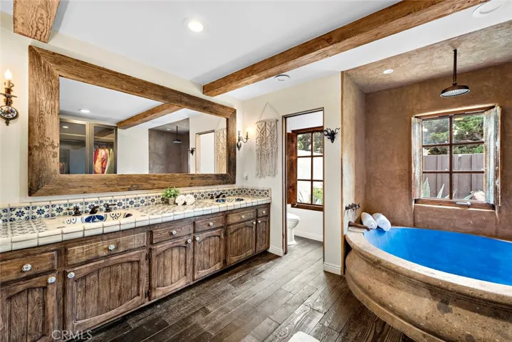 primary bathroom offers dual sinks, tub/shower and rustic charm