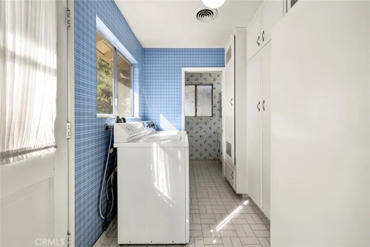 Indoor laundry with storage. 1/4 bath located off of the laundry area. To the left is the side entrance to the home from the driveway.