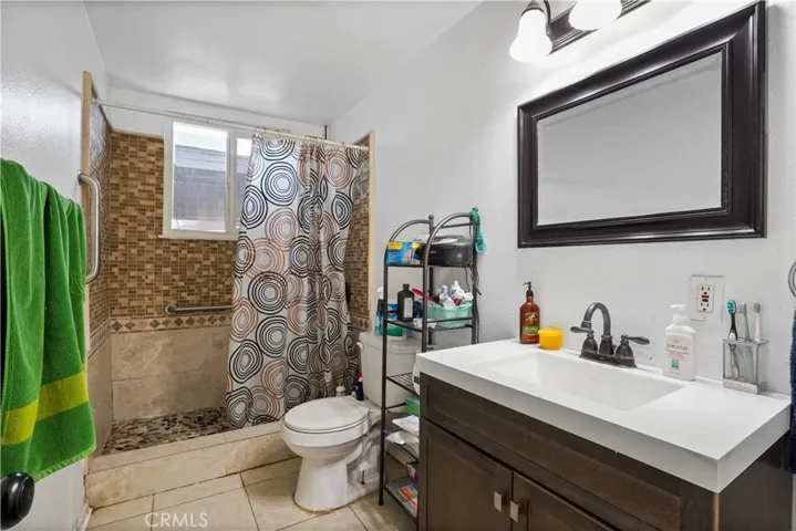 Hallway Bathroom 1- Walk-in shower with stone flooring and decorative Spanish tiled backsplash.