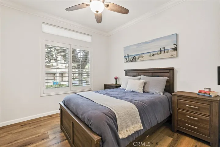 The secondary bedroom features a vinyl plank floor, ceiling fan with light, plantation shutters and closet with barn door closet doors and organizers.