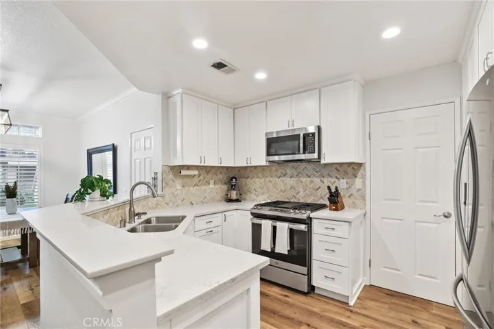 The light and bright kitchen also has a raised quartz covered angled counter, trash pull out to the right of the sink and a lazy susan corner.