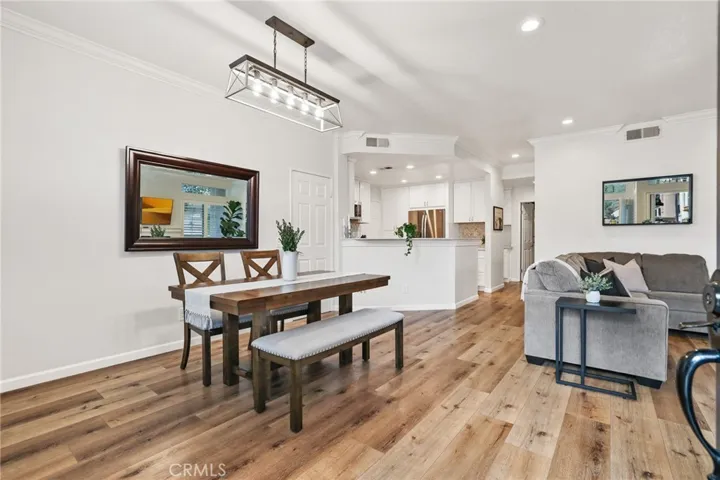 The dining room features a newer lighting fixture, vinyl plank flooring and crown molding.