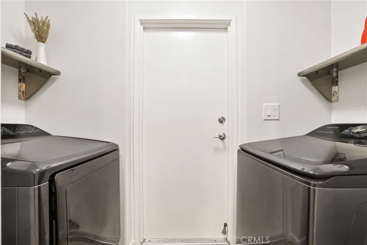 The laundry room is between the kitchen and garage and has a vinyl plank floor, light and storage shelves.