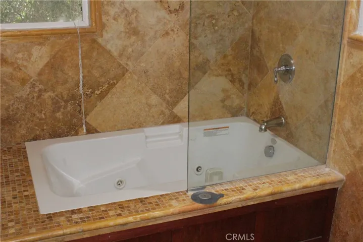 Jet tub, tile walls in shared bathroom