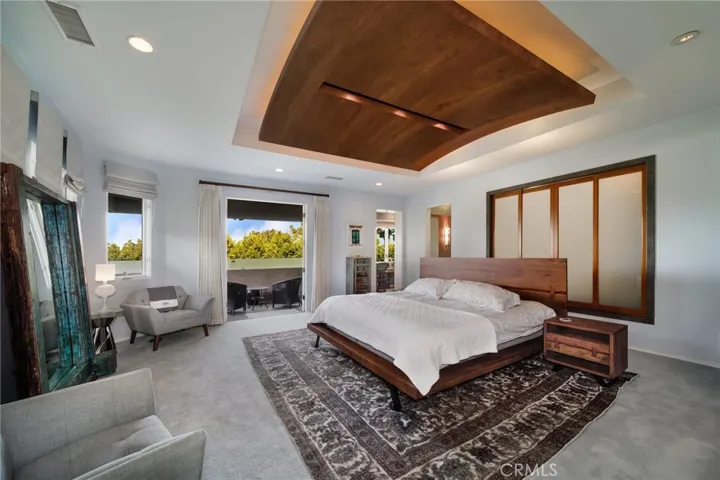 Master bedroom with curved wooden ceiling, custom lighting and attached balcony.