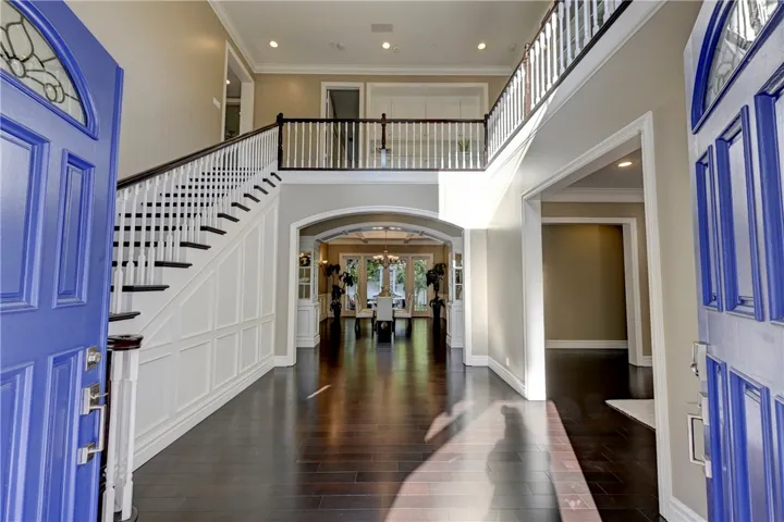 Enter through stunning blue doors to rich hardwood flooring, 2 story ceilings and custom wood work on the staircase.