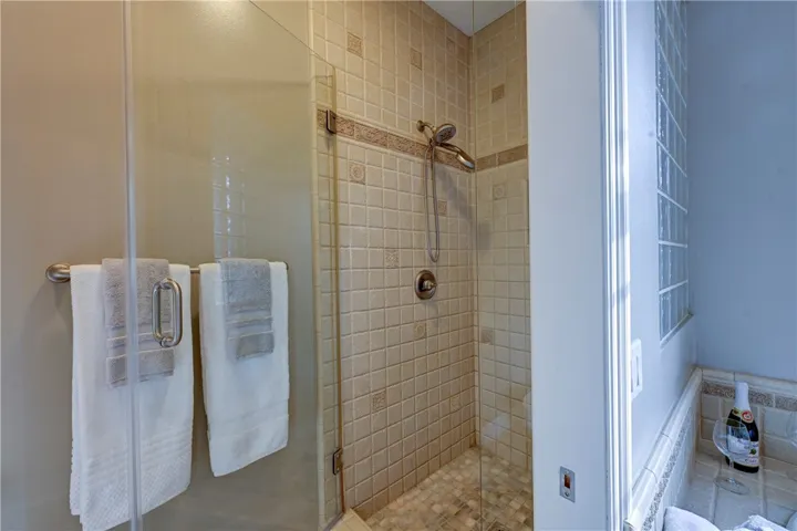 Primary private shower with dual shower heads and toilet area.