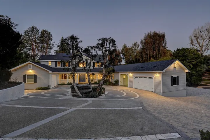 Circular driveway with a pond/fountain in the middle and additional parking on the extensive driveway marked with beautiful pavers.