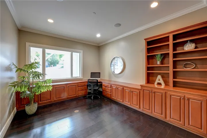 Spacious first floor office with built in desk, cabinetry and shelves.