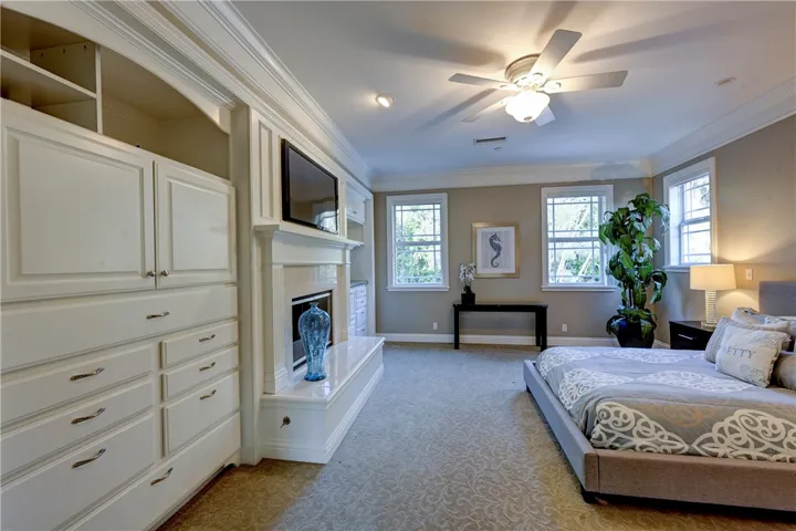 Primary bedroom with custom drawers, a gas starter fireplace, ceiling fan, and recessed lighting.
