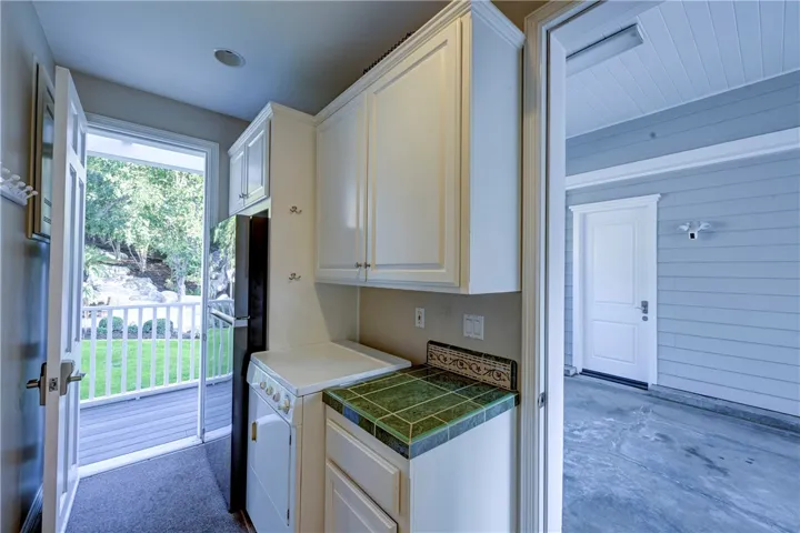 Doorway right off pool and backyard with refrigerator for snacks and an extra dryer for bathing suits and towels. The door on the right is direct access to the carport.