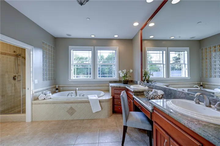 Primary bath with dual sinks, relaxing tub, and a private shower and toilet.