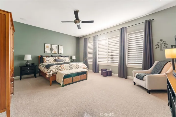 Spacious primary bedroom with ceiling fan and window view of the backyard.