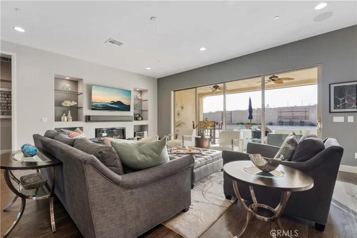 Beautiful living room with gas fireplace, wood floors, recessed lights, 10' foot high ceilings. California sliding doors to the outdoor living and pool.