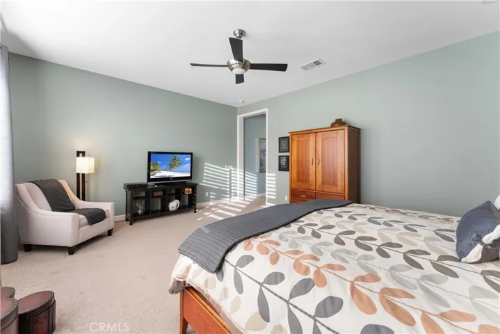 Spacious primary bedroom with ceiling fan and window view of the backyard.