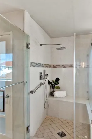 Primary Suite Walk-In Shower has Designer Tile with Inlay and a Sitting Bench