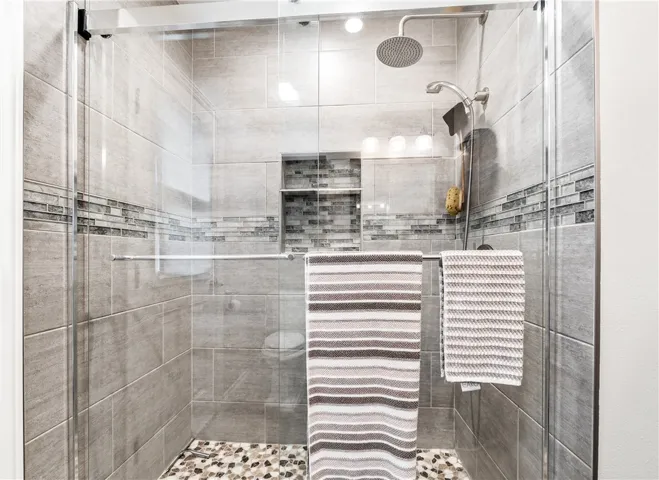 Custom walk-in shower, beautifully remodeled with plenty of storage and glass doors.