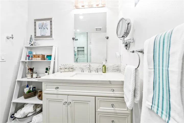 Primary bathroom, completely remodeled. Light and bright with custom cabinet, quartz counter, and storage shelf which conveys.
