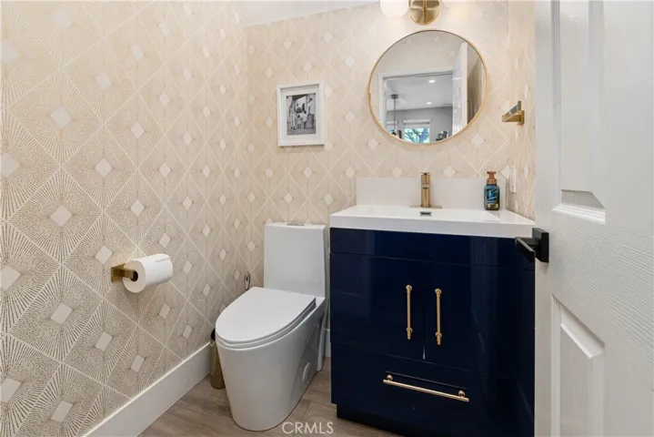 Stylish powder room with new toilet and vanity, and custom wallpaper.