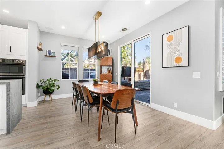 Dining enclave is modern with custom chandelier, new flooring, and sliding door to outdoor veranda.