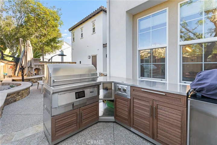 Entertainers backyard with large fireplace, custom outdoor kitchen with grill/smoker, refrigerator, outdoor tv.