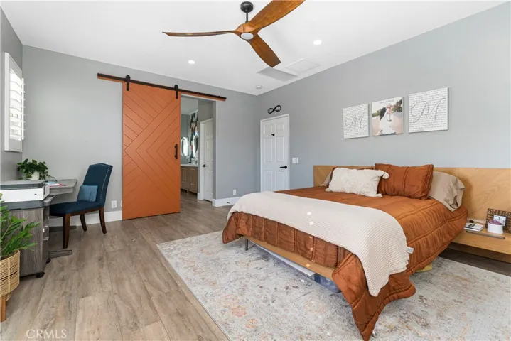 Owner's suite has custom barn door, Juliet balcony, new flooring, ceiling fan, custom shutters.