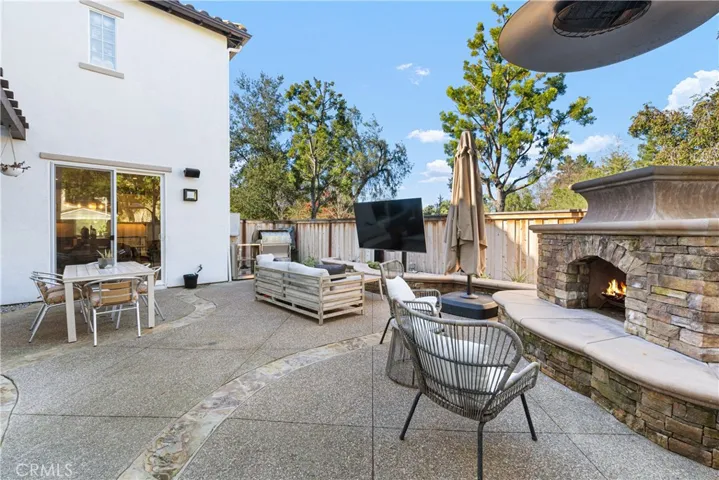 Entertainers backyard with large fireplace, custom outdoor kitchen with grill/smoker, refrigerator, outdoor tv.