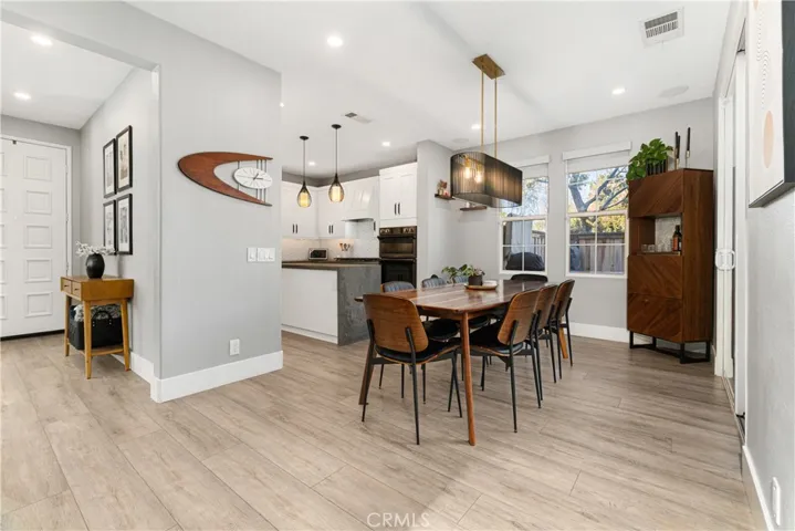 Dining enclave is modern with custom chandelier, new flooring, and sliding door to outdoor veranda.