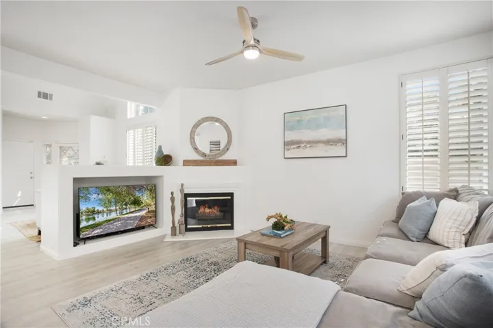 Cozy family room with large media niche, corner fireplace, ceiling fan and shutters