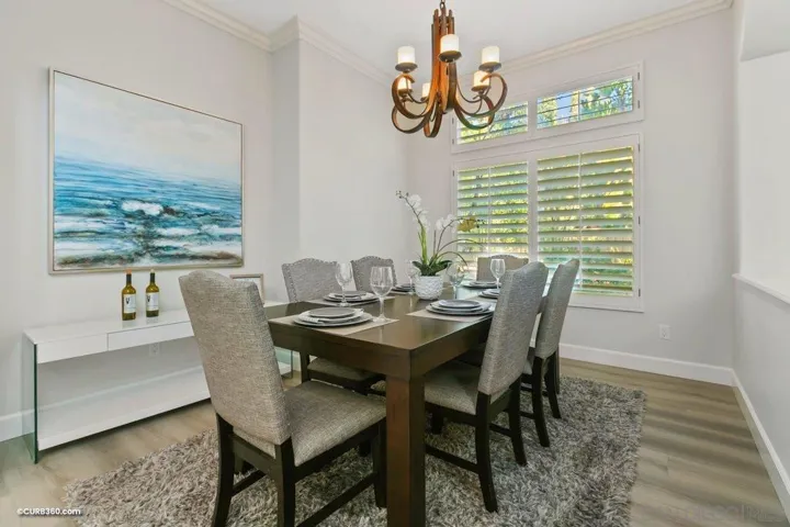 Elegantly decorated formal dining room surrounded by tall windows with plantation shutters and views of the plush side yard