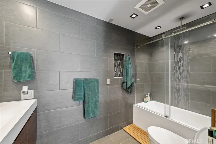 Bathroom has Tile Flooring, Tile Walls with Custom insert tiles in the Shower, Large Tub and Shower with Rain Shower Faucet, and Glass Doors.