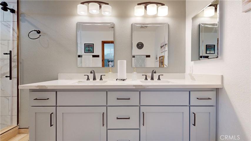 upgraded master bathroom with giant walk in shower w/ 3 shower heads, built in corner bench, sliding glass door and recessed shower caddy. Custom lighting, mirrors and quartz countertop. Vanity with soft-close hardware.