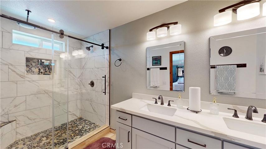 upgraded master bathroom with giant walk in shower w/ 3 shower heads, built in corner bench, sliding glass door and recessed shower caddy. Custom lighting, mirrors and quartz countertop. Vanity with soft-close hardware.