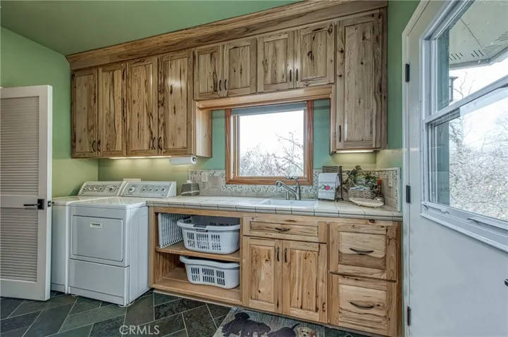 Large Laundry with custom build Hickory cabinets a sink and plenty of storage space.