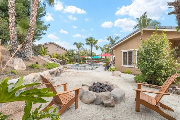 Nestled in the tranquility of a private backyard, a miniature sandy beach offers a personal oasis beside the inviting waters of a serene pool.