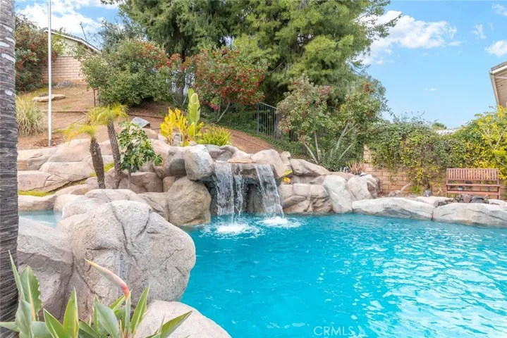 A picturesque pool with cascading waterfalls set against a backdrop of tropical palms and rocky features.