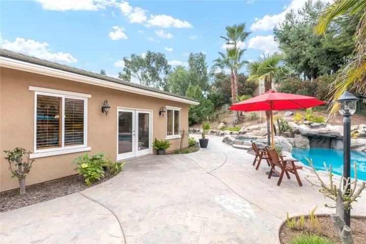 A charming pool house stands as a cozy haven, complemented by the surrounding vibrant greenery and the gentle ripple of the crystal-clear pool waters.