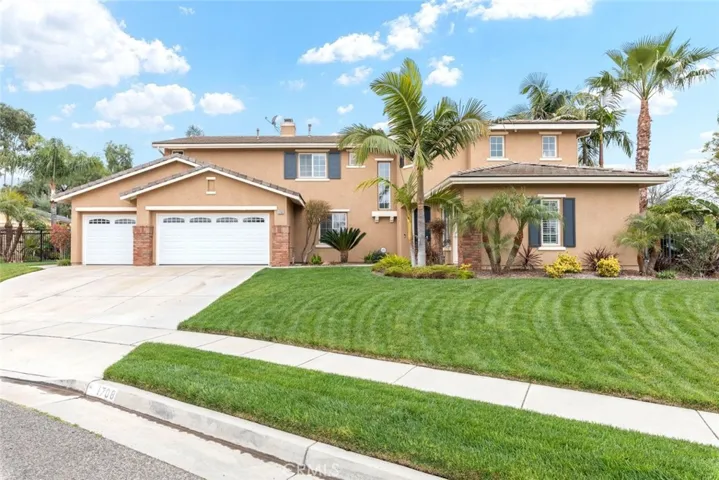 Palm trees and vibrant greenery frame the entrance to this charming suburban home, promising tranquility within.
