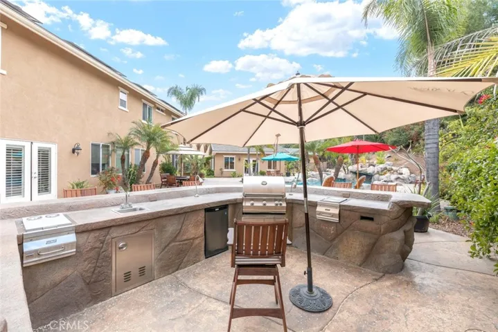 An entertainer's dream, with an outdoor BBQ and poolside lounging under sunny skies