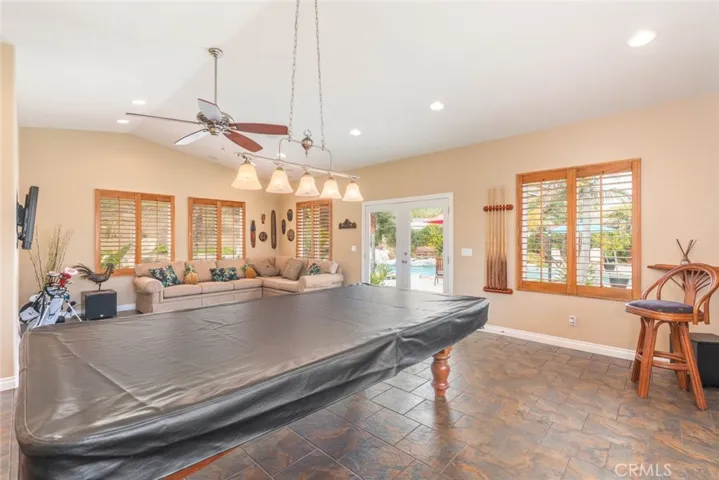 A spacious game room with ample natural light and direct access to a sunny poolside patio.